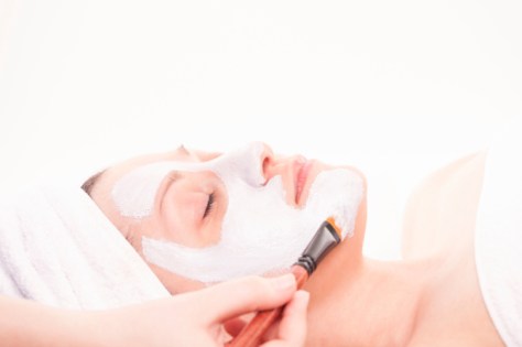 Beautiful young woman getting facial mask applied